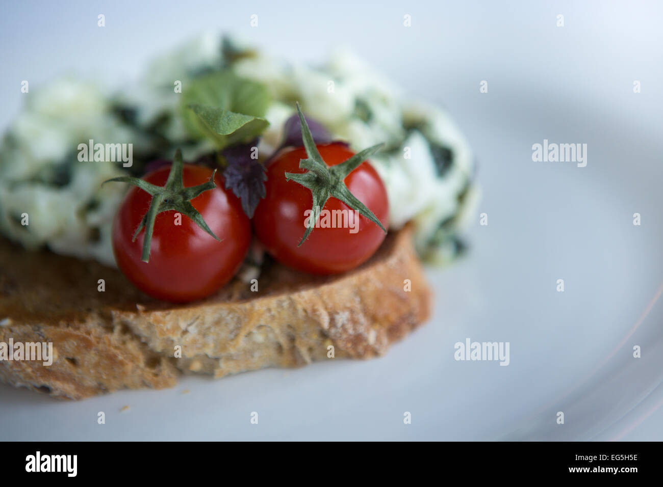 Scrambled egg whites with spinach, cherry tomatoes on a slice of toasted wholemeal bread. Stock Photo