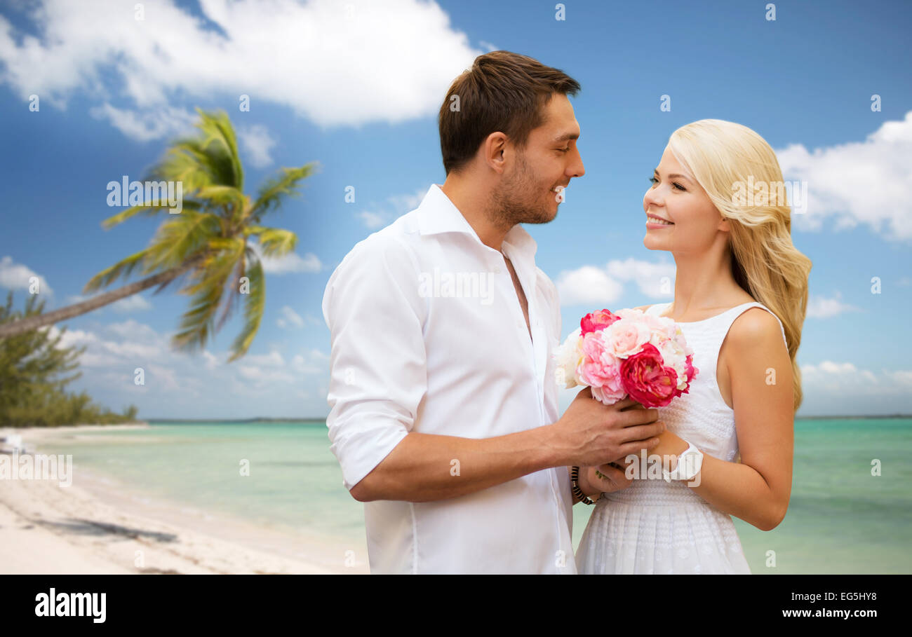 happy couple with flowers over beach background Stock Photo - Alamy