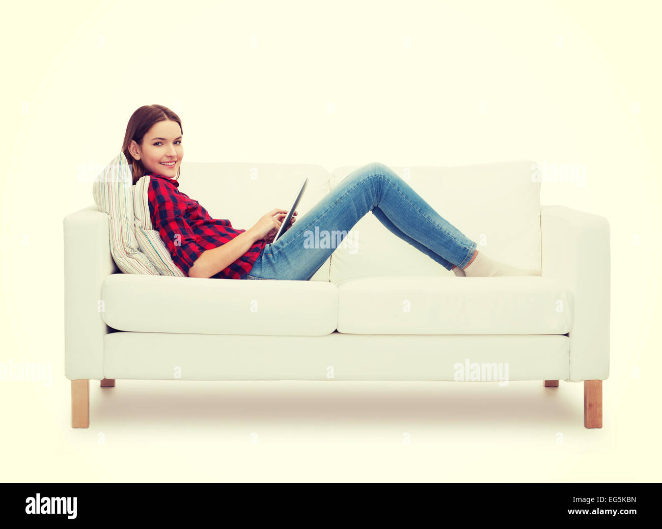 teenage girl sitting on sofa with tablet pc Stock Photo - Alamy