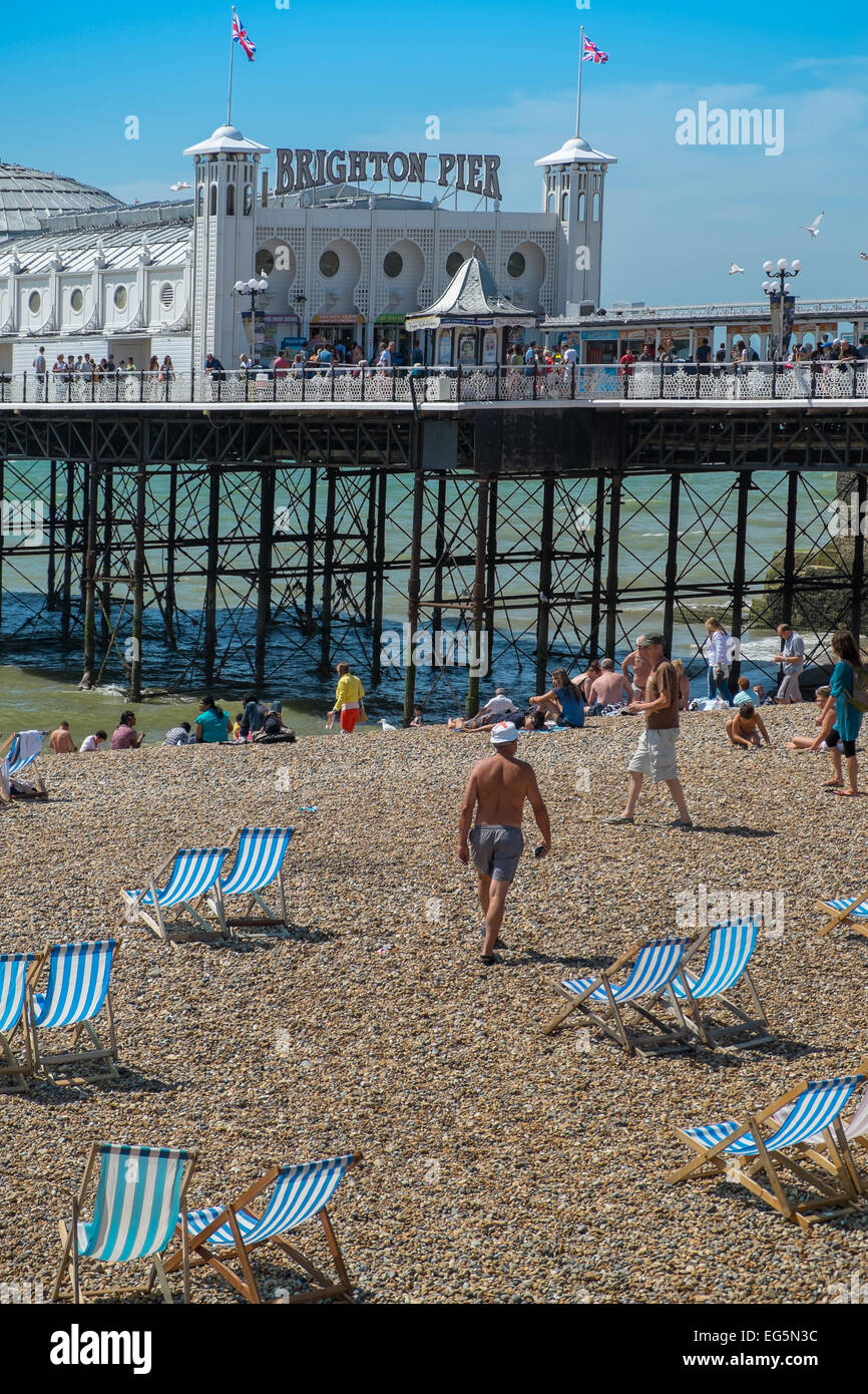 BRIGHTON, UK- JULY 28, 2013: People enjoying a rare sunny day on Brighton Beach in front of the famous Pier on July 28th, 2013. Stock Photo