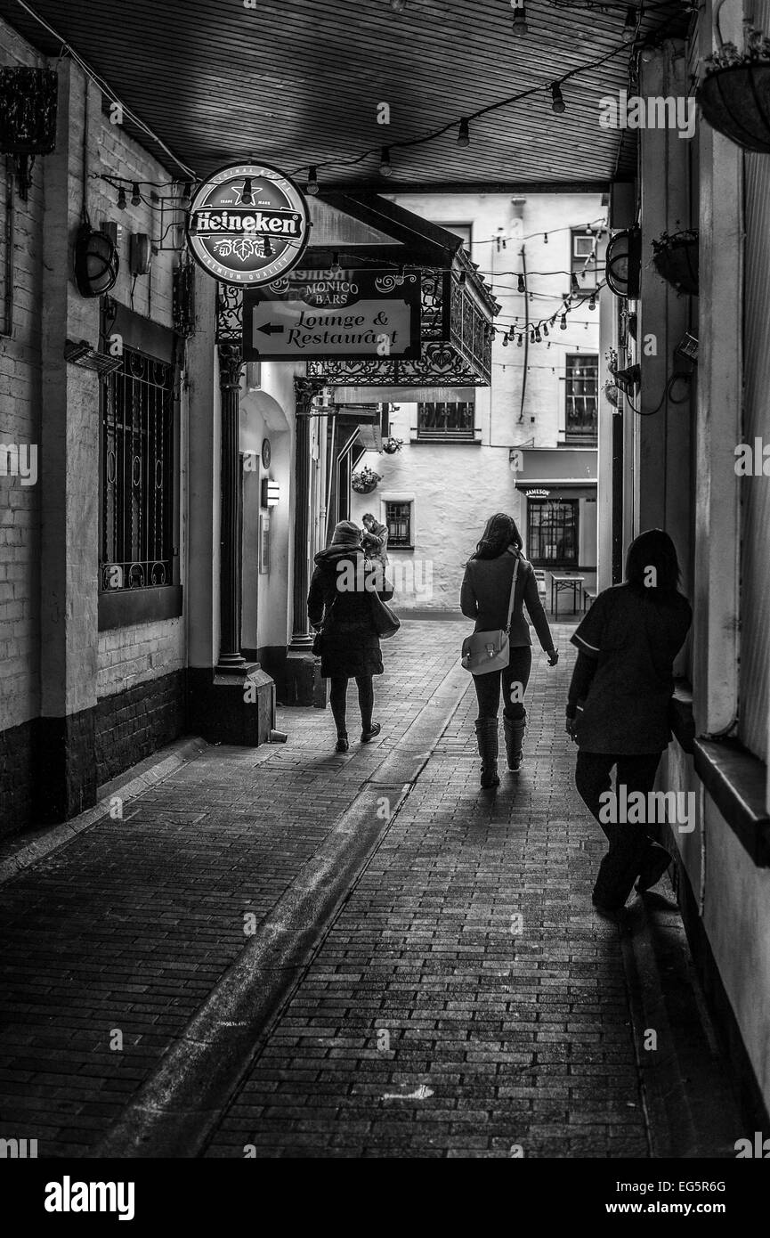 People walking through Winecellar Entry Belfast.  The photograph is rendered as a monochrome. Stock Photo