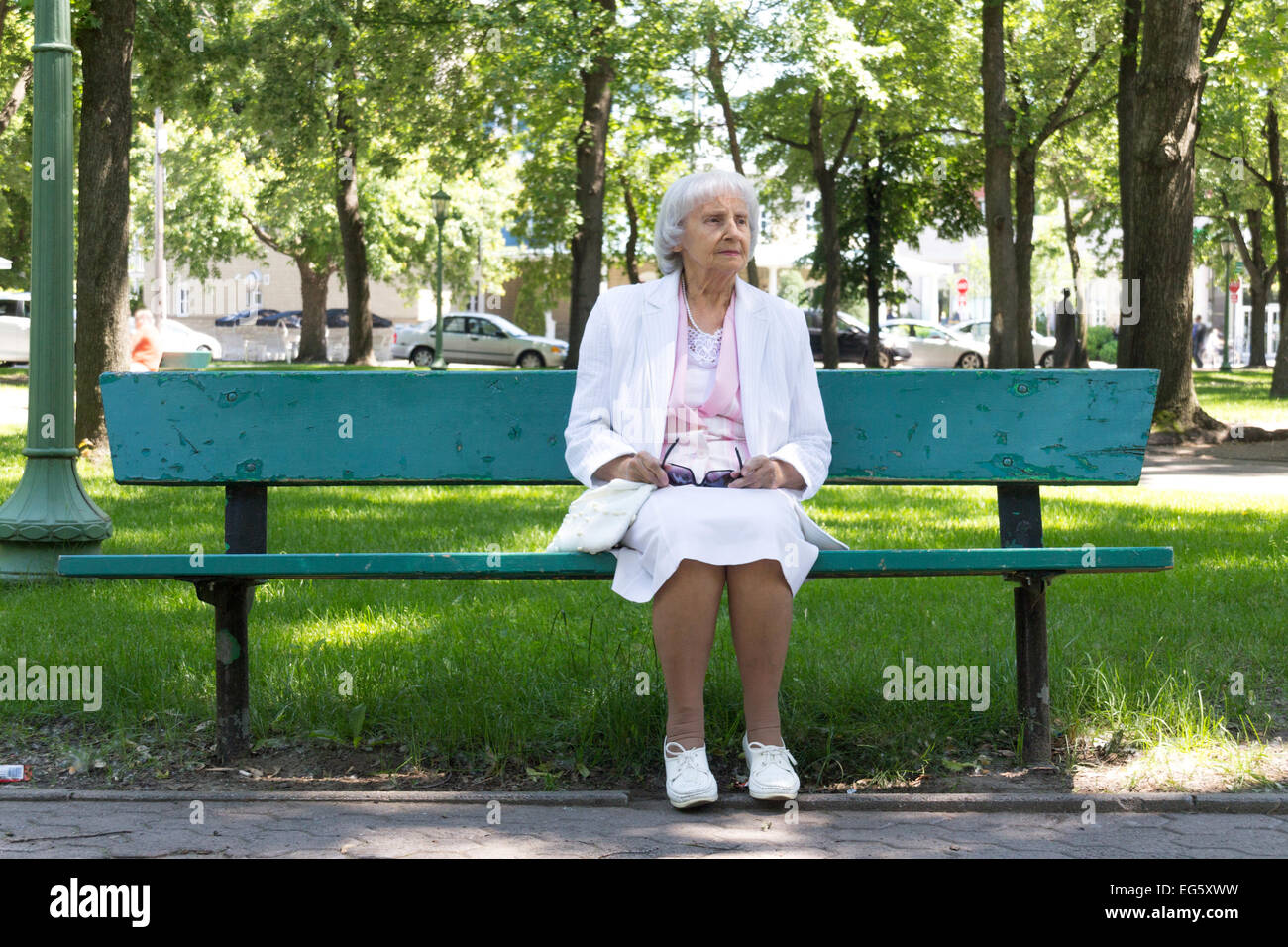 83 years old elderly woman sitting on a bench in a park Stock Photo