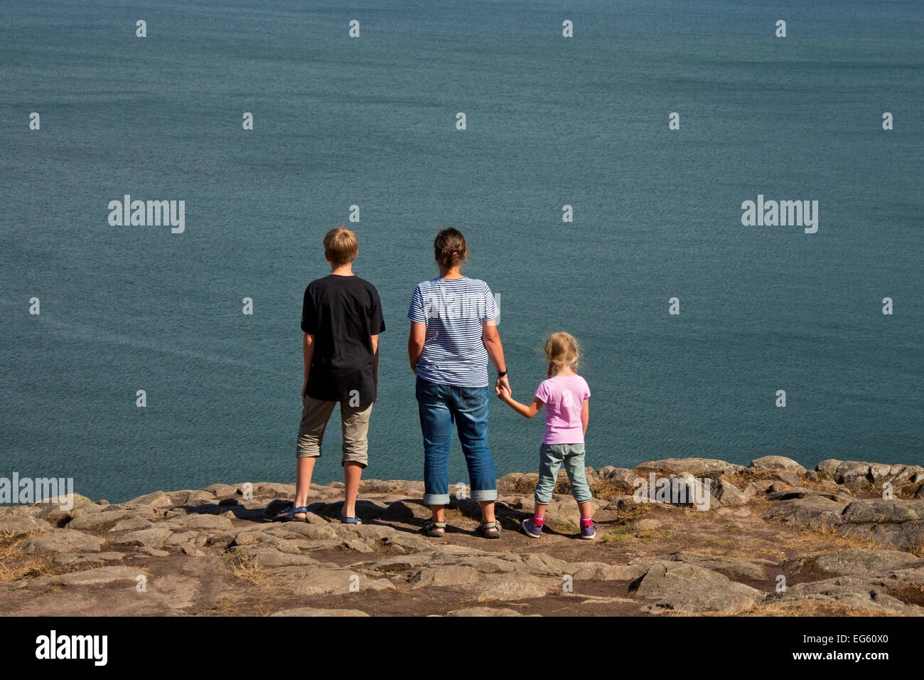 Family, mother with son and little daughter looking from cliff top over the sea Stock Photo