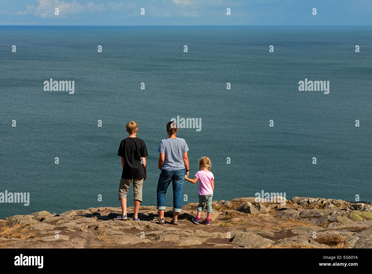 Family, mother with son and little daughter looking from cliff top over the sea Stock Photo