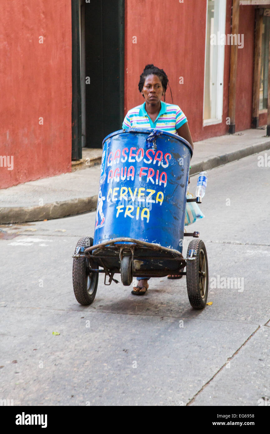 Cartagena, Colombia - February 22, 2014 - A vendor pushes her cart down the street selling cold beverages to workers and tourist Stock Photo