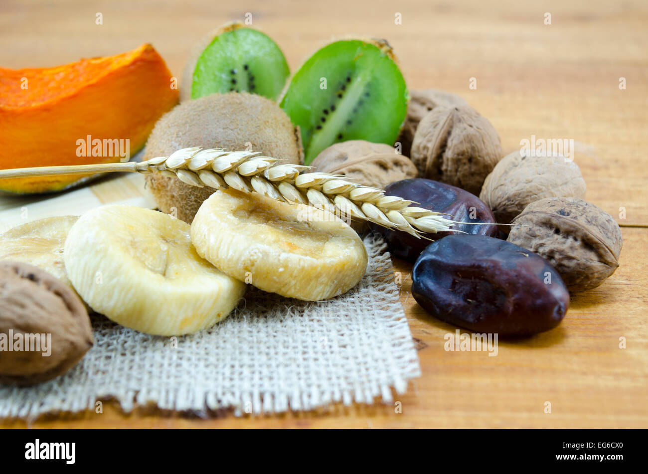 Dried figs, palms, pumpkins with walnuts and kiwis on a wooden table Stock Photo