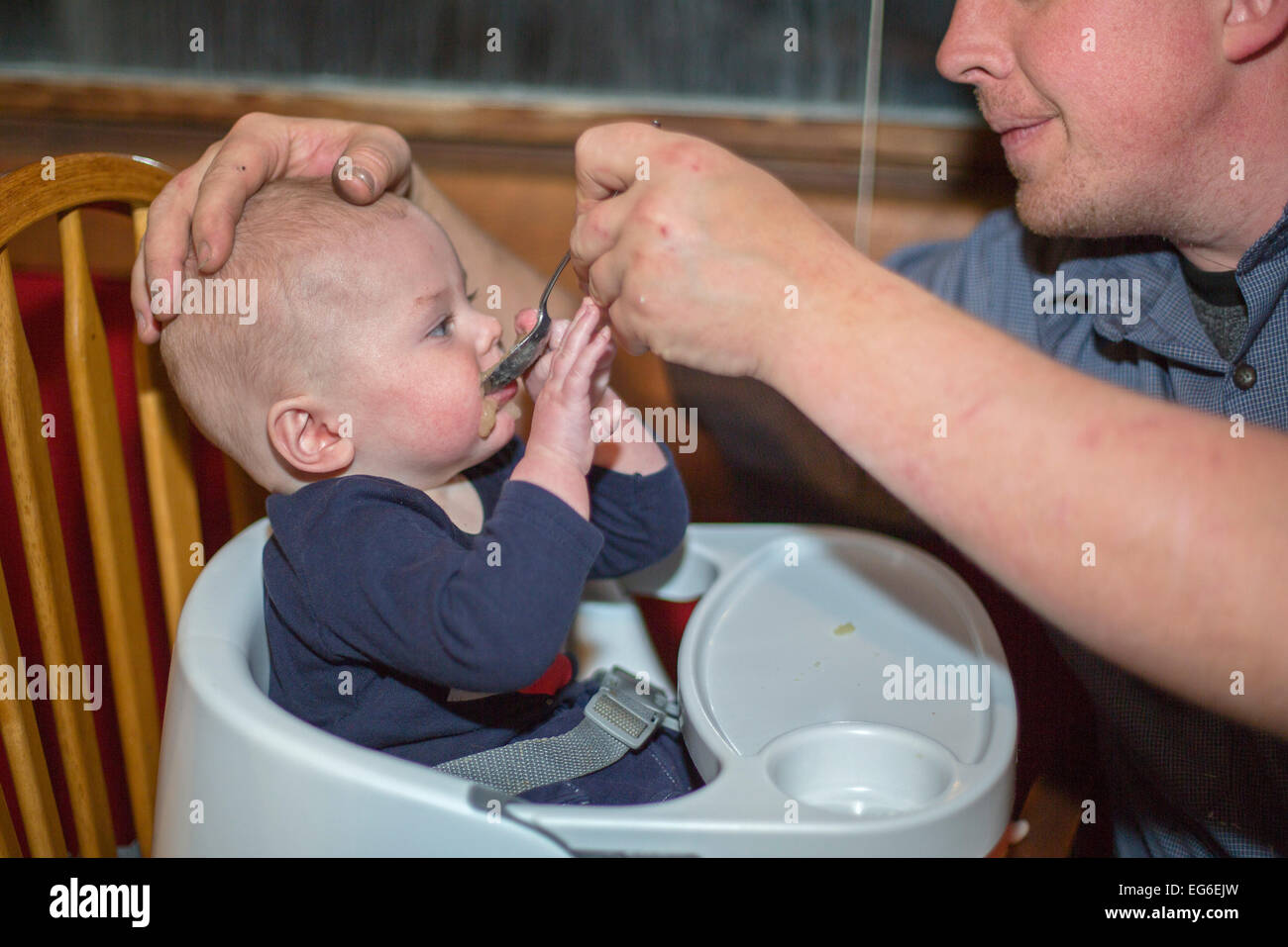 Denver, Colorado - Adam Hjermstad feeds applesauce to his seven-month-old son, Adam Hjermstad Jr. Stock Photo