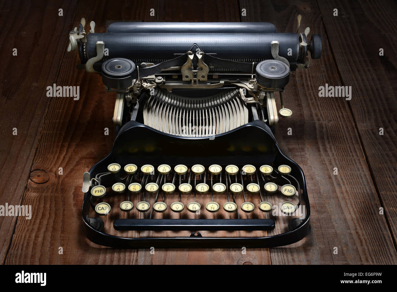 Overhead shot of an antique typewriter on a rustic wood table. Horizontal format with directional lighting. Stock Photo