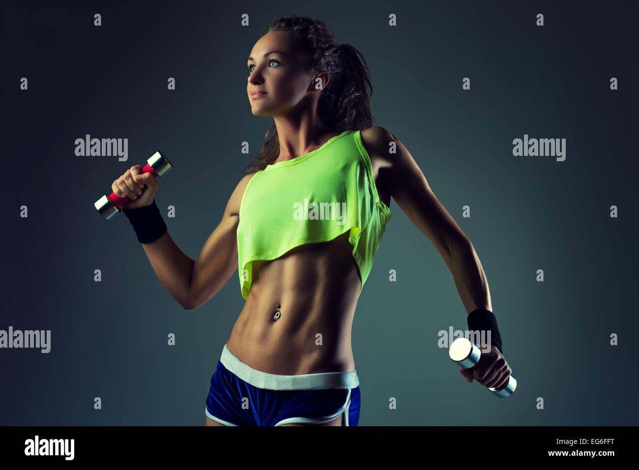 Young sports sexy fitness woman with dumbbells posing on wall background  Stock Photo - Alamy