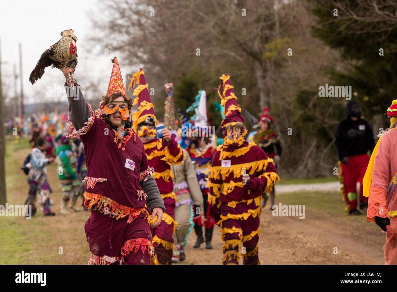 A costumed reveler holds up the chicken he caught during the Faquetigue
