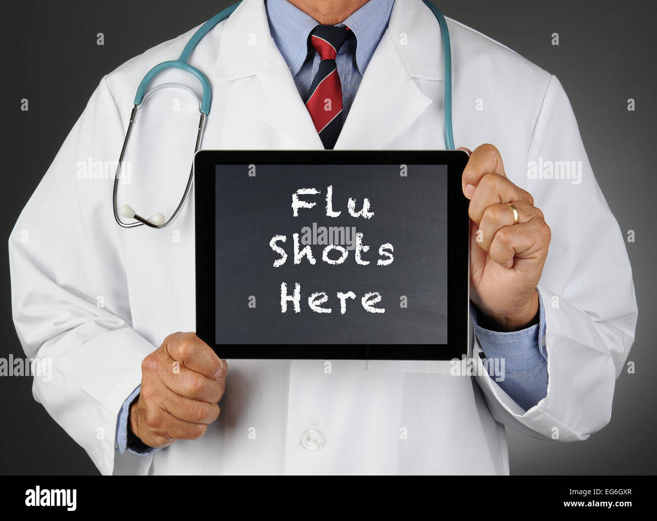 Closeup of a doctor holding a tablet computer with a chalkboard screen with the words Flu Shots Here. Man is unrecognizable. Stock Photo