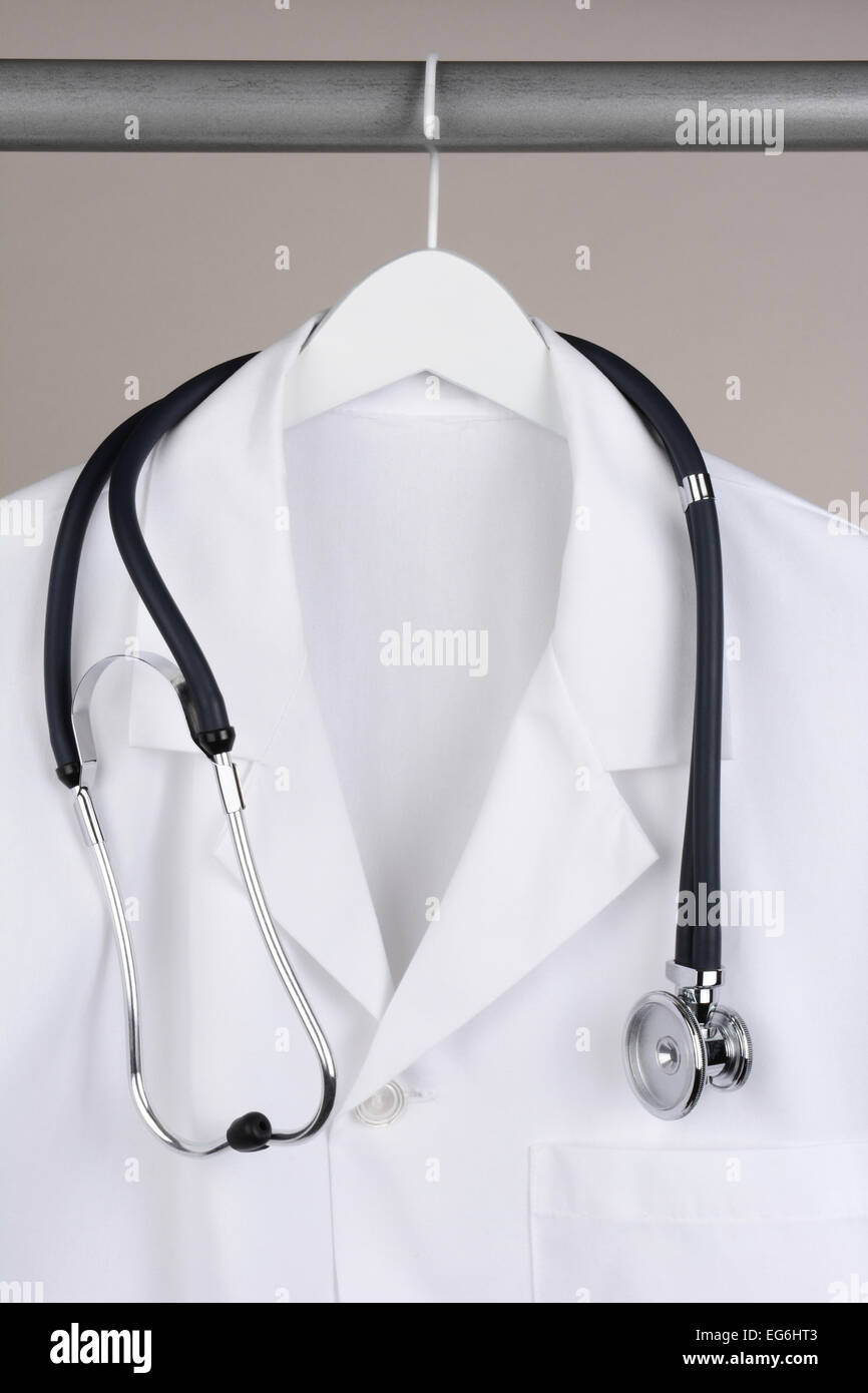 Closeup of a doctor's lab coat and stethoscope on hanger against a neutral background. White coat on a white hanger with a gray Stock Photo