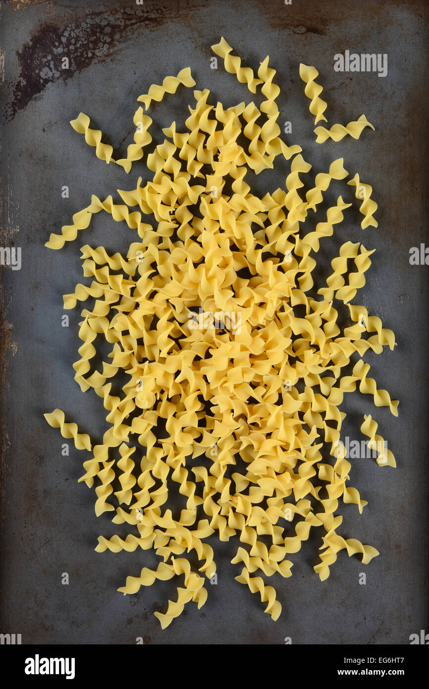 High angle shot of egg noodles scattered on a well used metal baking sheet. Vertical format. Stock Photo