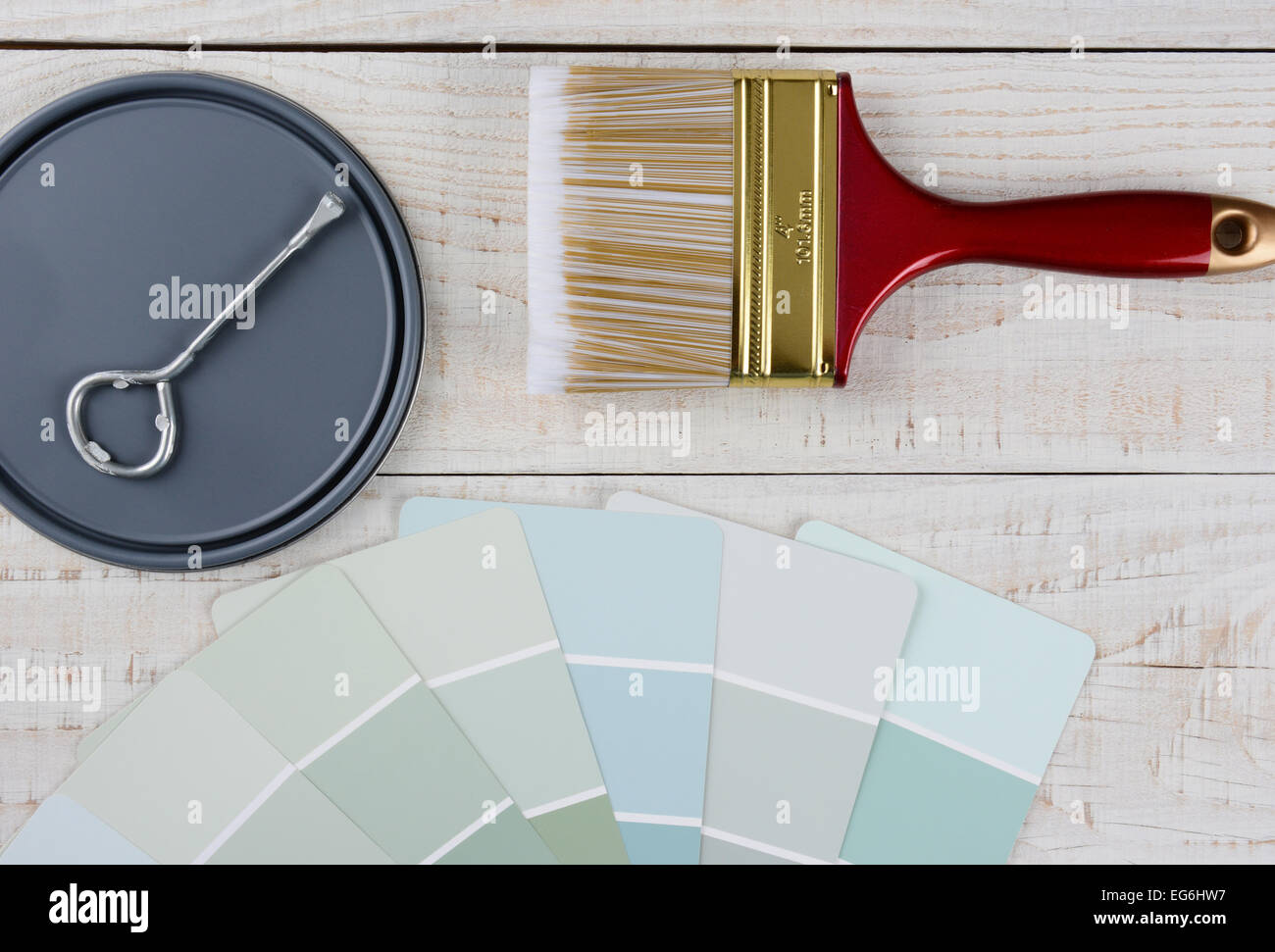 Overhead shot of  a paint can lid, opener, color samples and paint brush on a rustic wooden surface. Horizontal format with copy Stock Photo