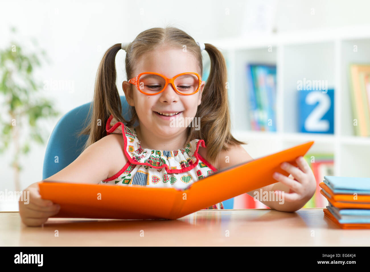 Happy funny child girl in glasses reading a book Stock Photo