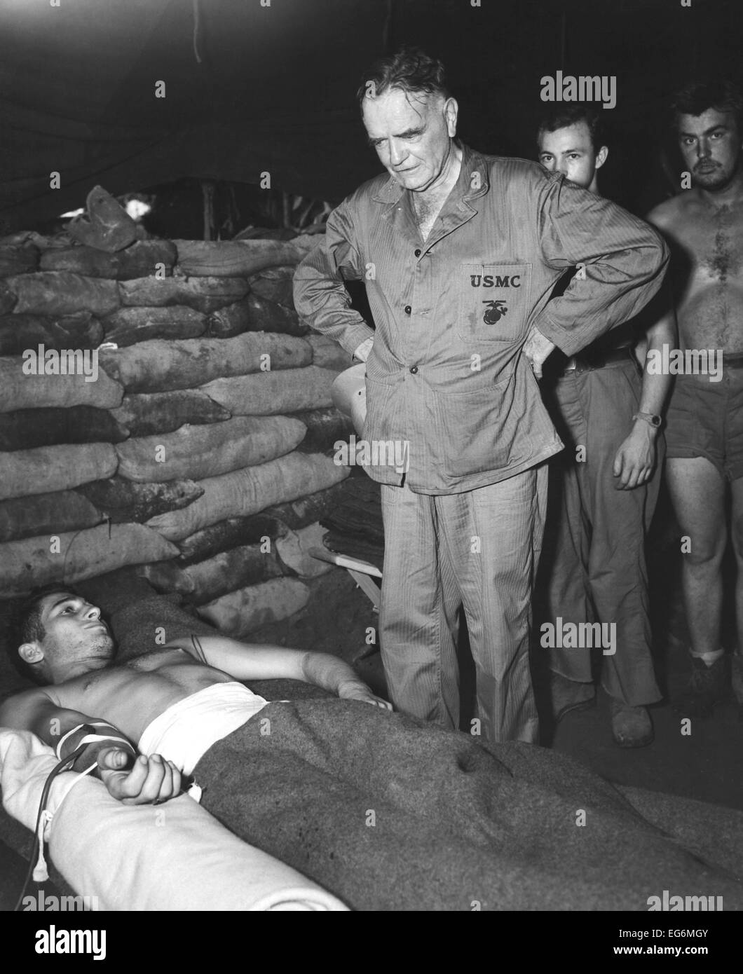 Admiral William Halsey visiting a sandbagged hospital dugout at Bougainville. The soldier is receiving a saline injection after Stock Photo