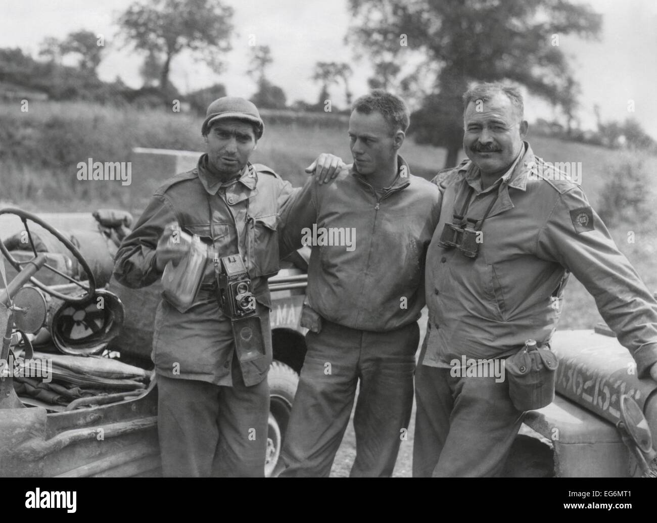 Robert Capa (left) and Ernest Hemingway (right) with their driver U.S. Army driver. They are waiting to follow an American Stock Photo