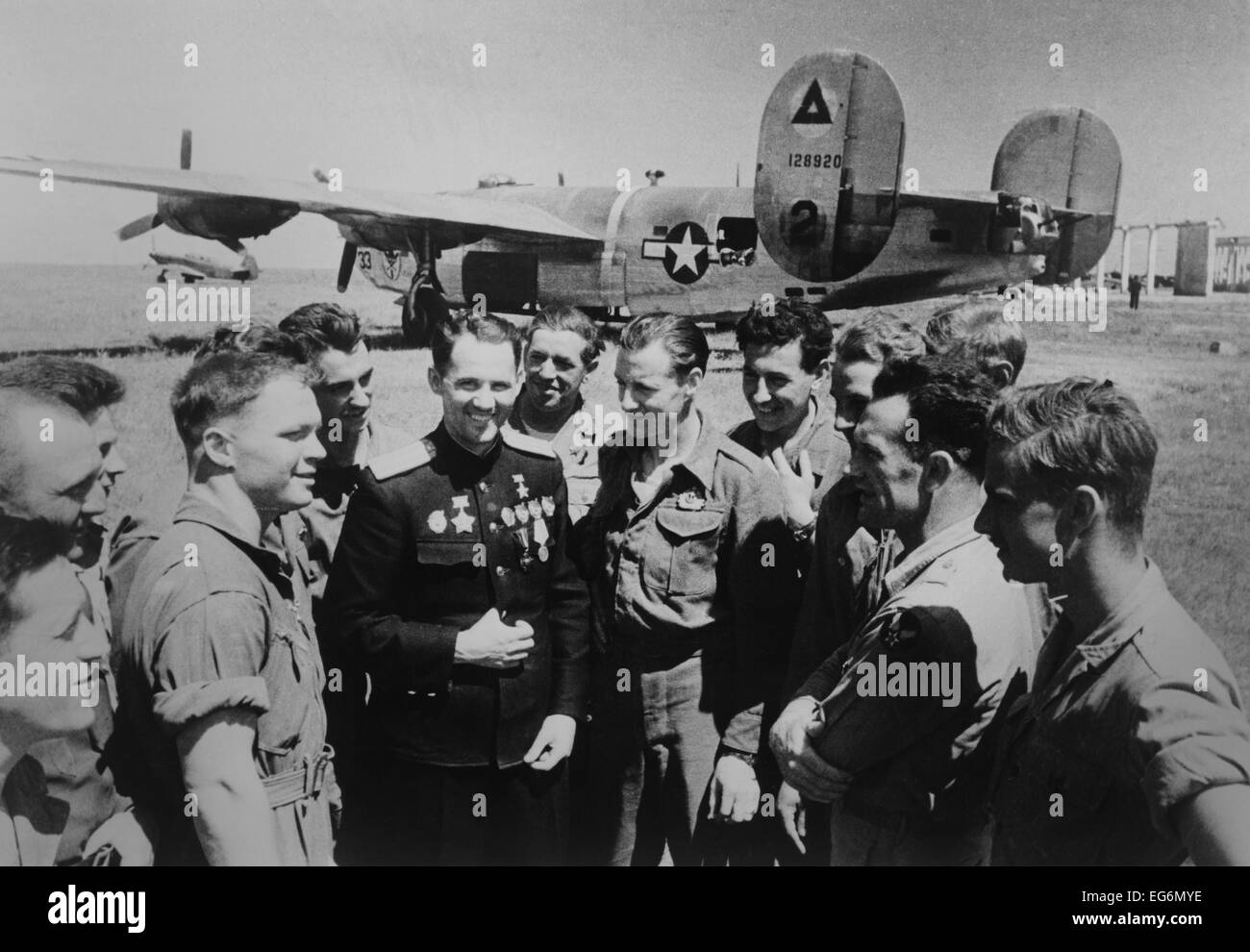 Soviet (Russian) World War 2 ace Mikhail Avdeev with American pilots. In the background is a Consolidated B-24 Liberator Stock Photo