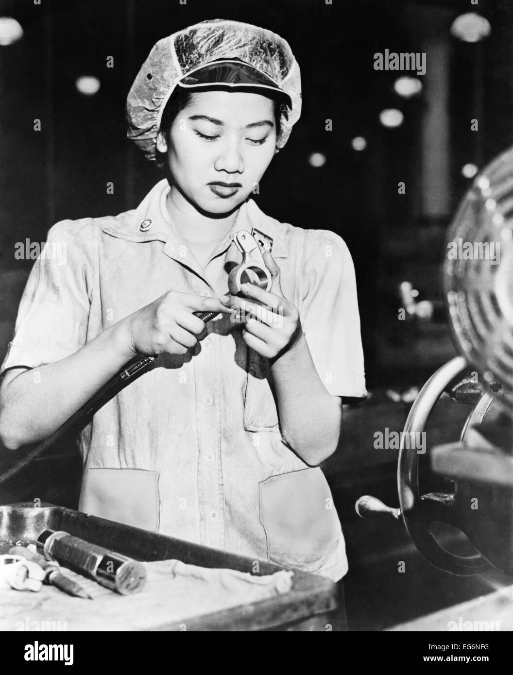 Wong Ruth Mae Moy working on an American aircraft engine part. She is a young Chinese women who survived the Canton bombings. Stock Photo