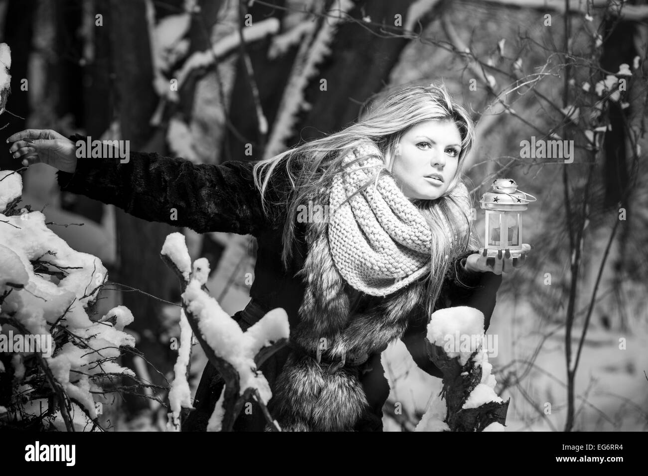 Scared young woman with candle in forest. Black and white image Stock Photo