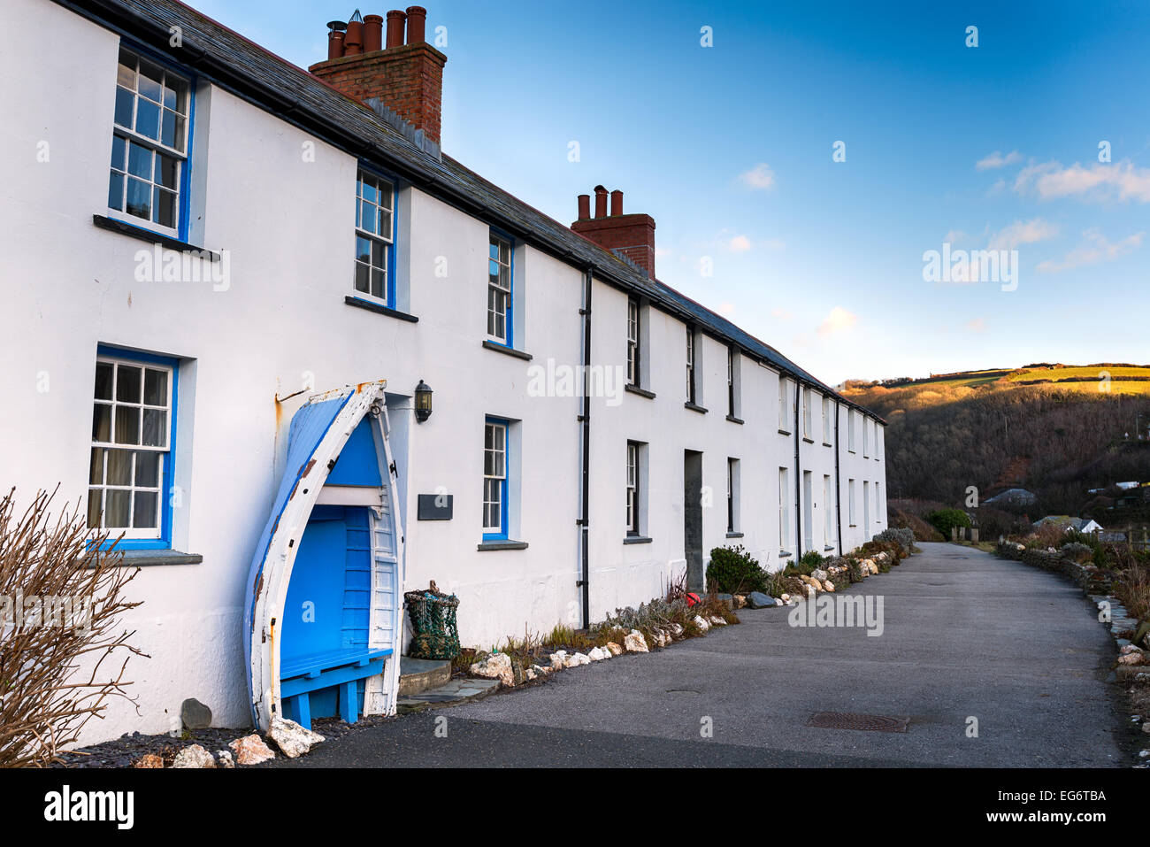 A row of white terraced cottages with an old boat seat at Boscastle in Cornwall Stock Photo