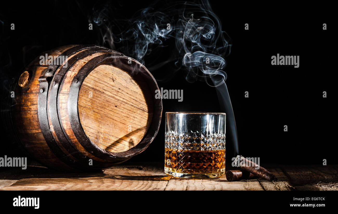 Glass of alcohol and smoking noble cigar on a black background Stock Photo