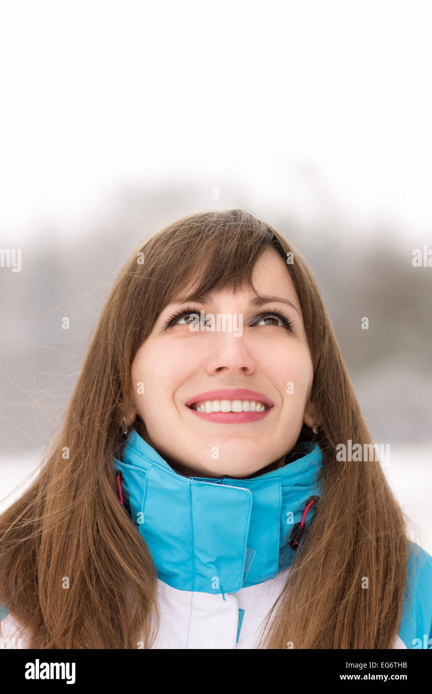 Young caucasian woman looking on copy space in outdoor snowy cold winter day. Stock Photo