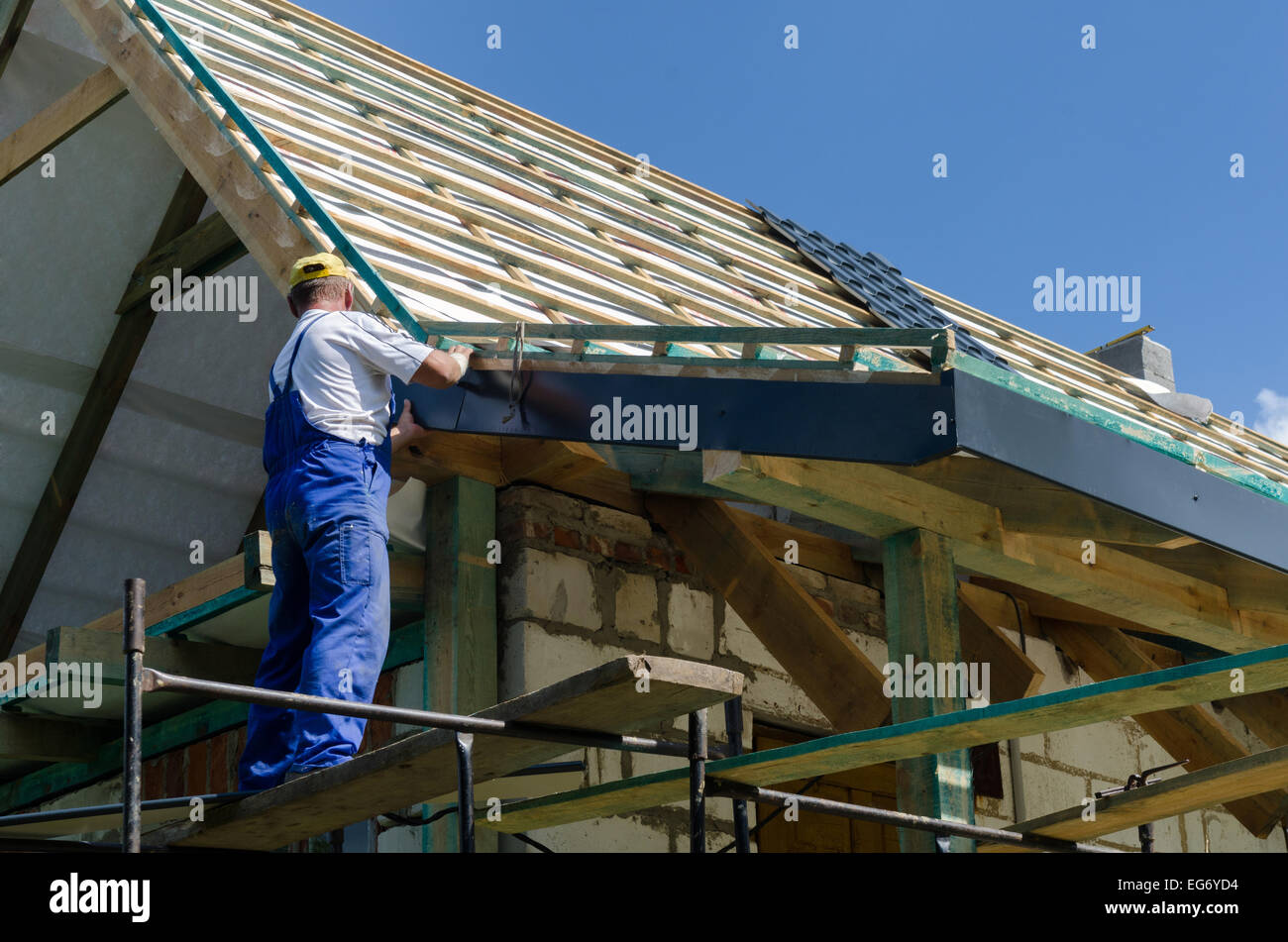 A worker standing on the scaffolding and finishing a roof Stock Photo