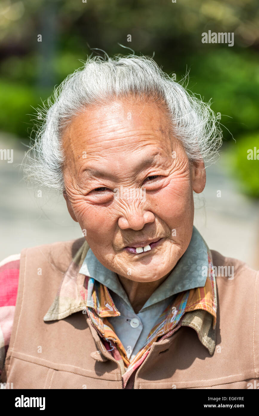 Shanghai, China - April 7, 2013: old chinese woman friendly toothless toothy smiling outddors portrait at the city of Shanghai in China on april 7th, 2013 Stock Photo