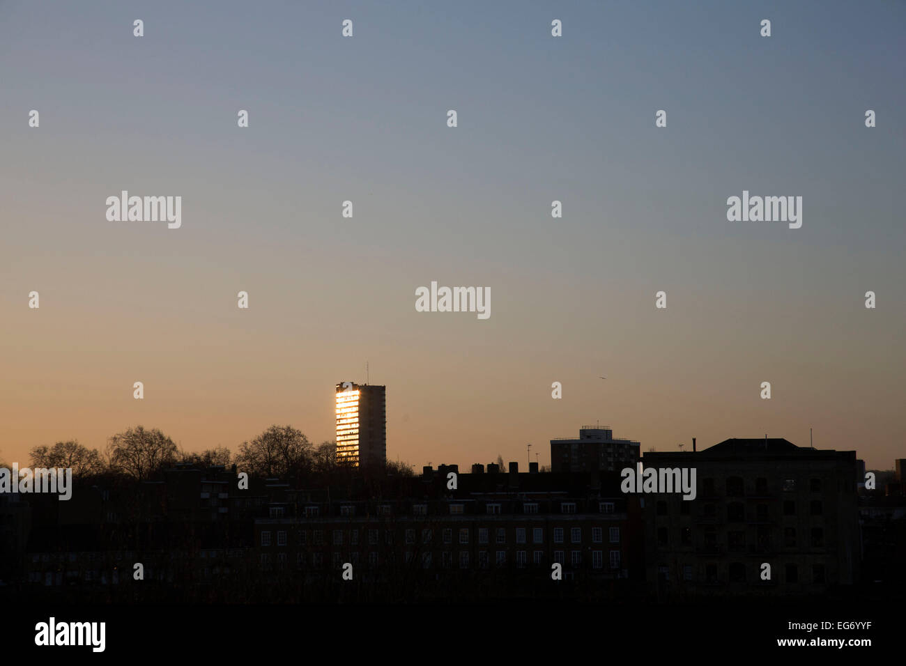 Sunrise reflected in a tower block in South East London, UK. From the same position about two days each year the sun lines up perfectly with this council block and reflects the rising sun directly. Stock Photo
