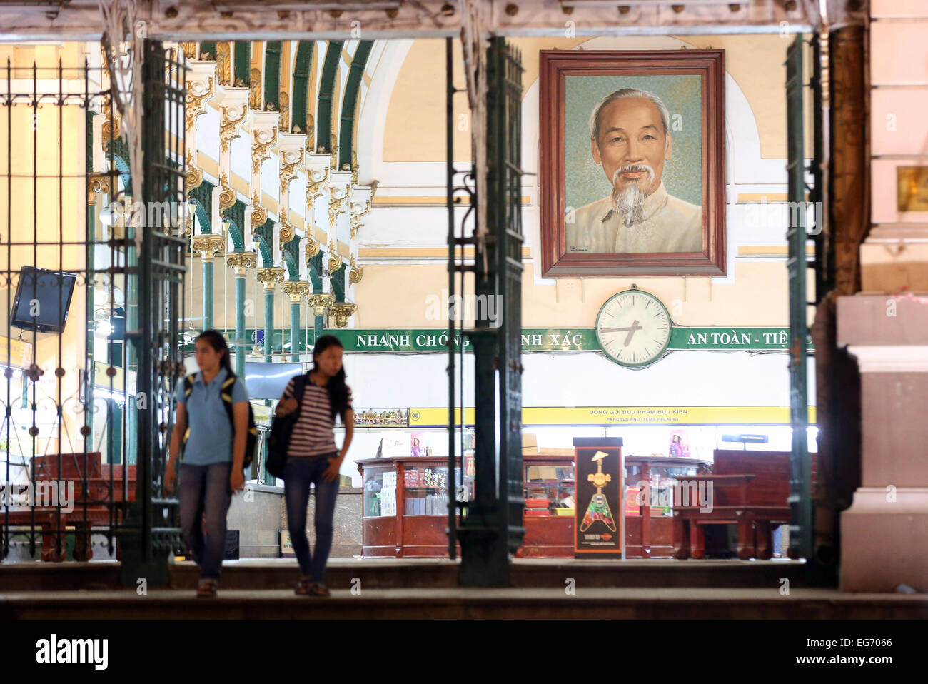 Two women are leaving a post office in Ho Chi Minh City on 21st November 2014. A portrait of Ho Chi Minh is hanging on the wall. Stock Photo