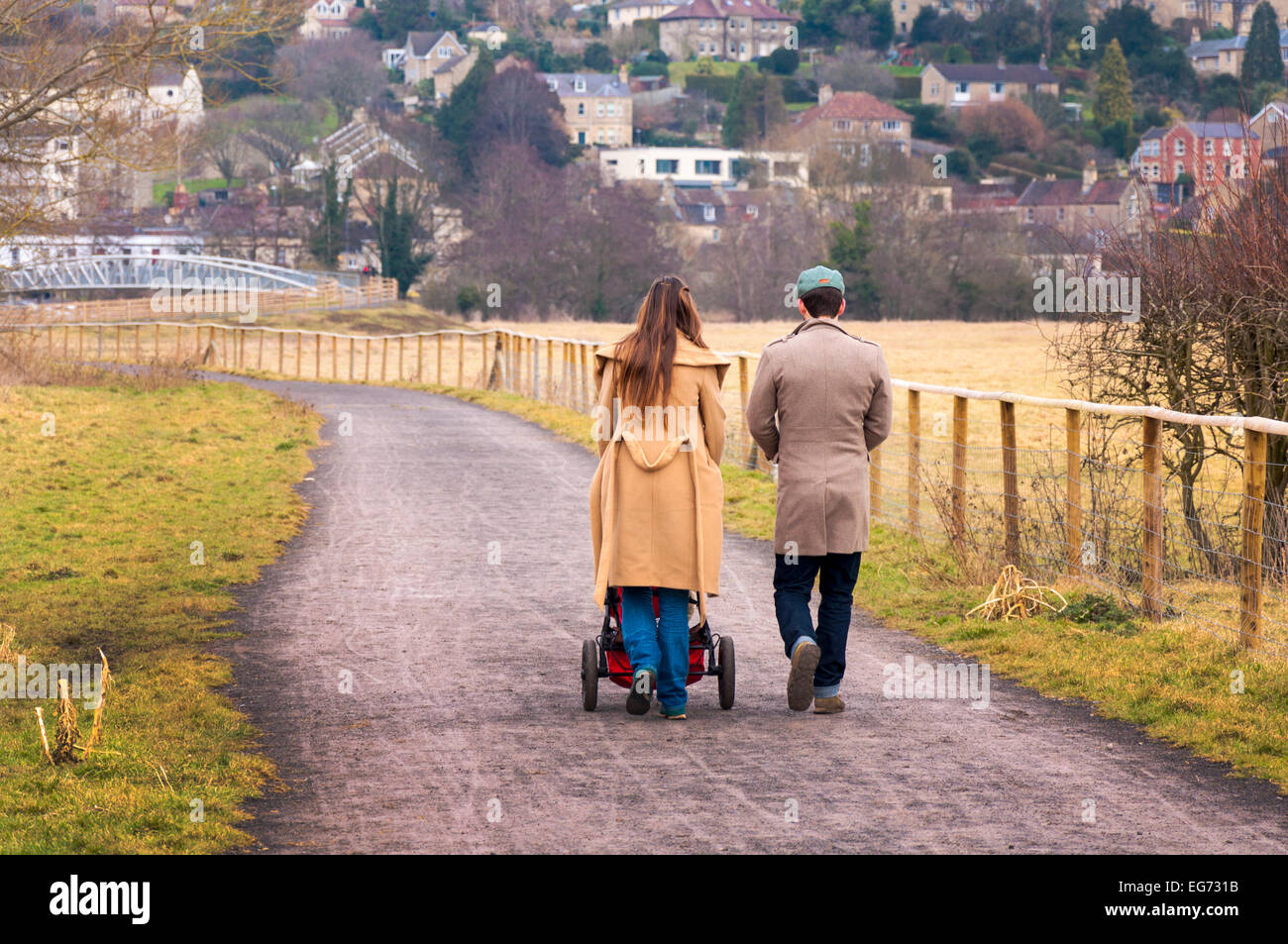Young couple walking with baby in pushchair Stock Photo