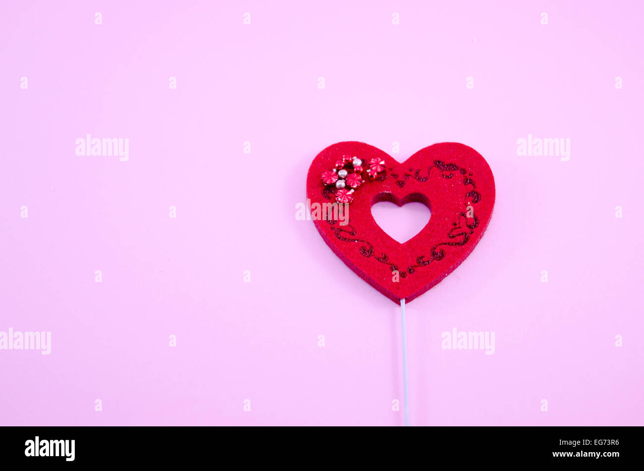Red engraved heart on pink paper with some shiny pearls Stock Photo