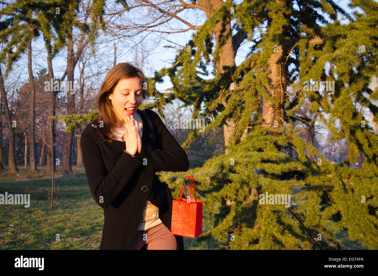 Brunette finding her Valentine's gift on a tree in a park Stock Photo