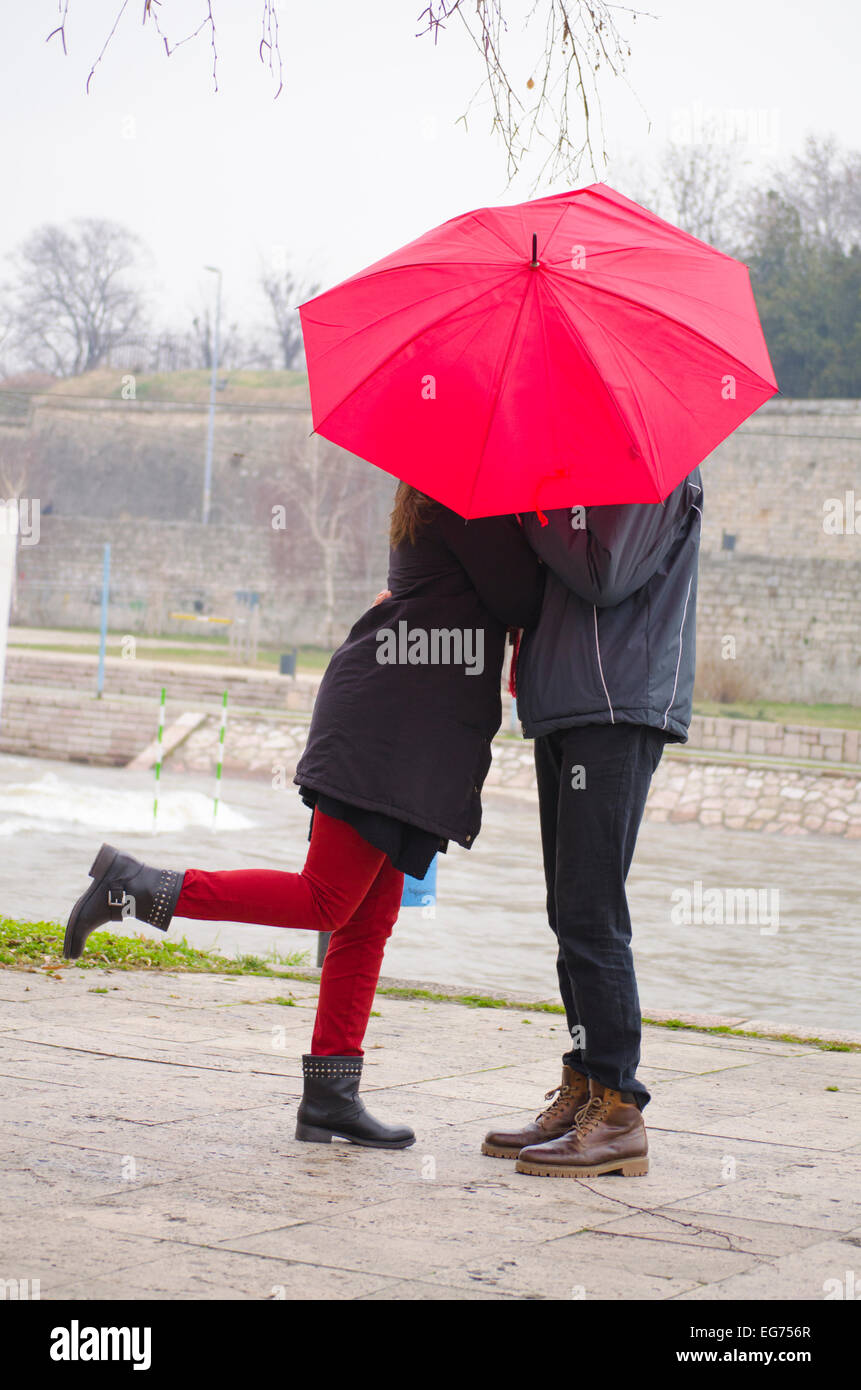 Couple kissing behind an umbrella, outdoors, close to the river Stock Photo