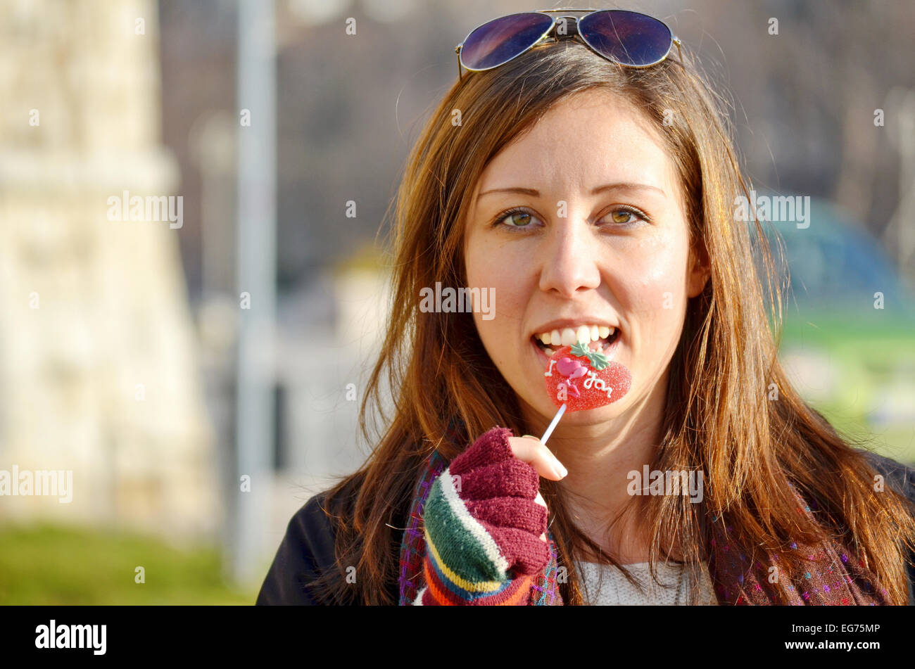 Girl biting heart shape candy on a sunny day outdoors Stock Photo