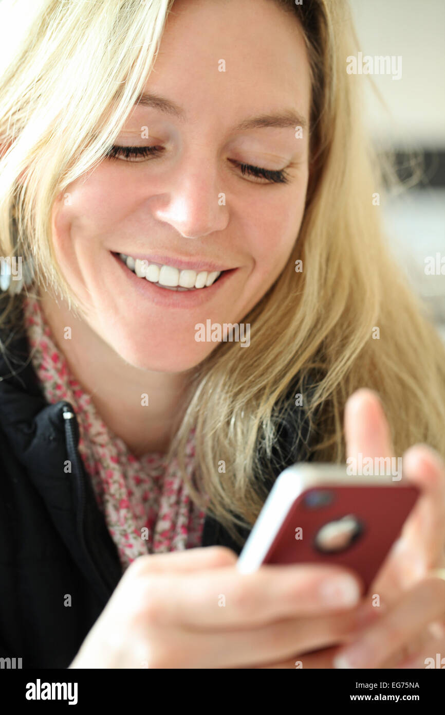 Smiling blond lady using a cell phone Stock Photo