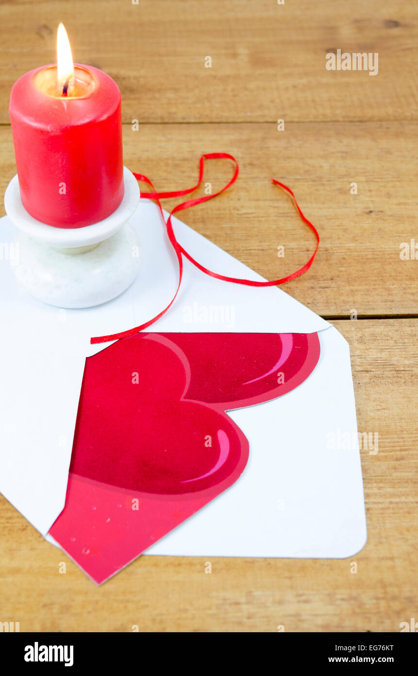 Red burning candle and a heart shaped Valentine's day card Stock Photo