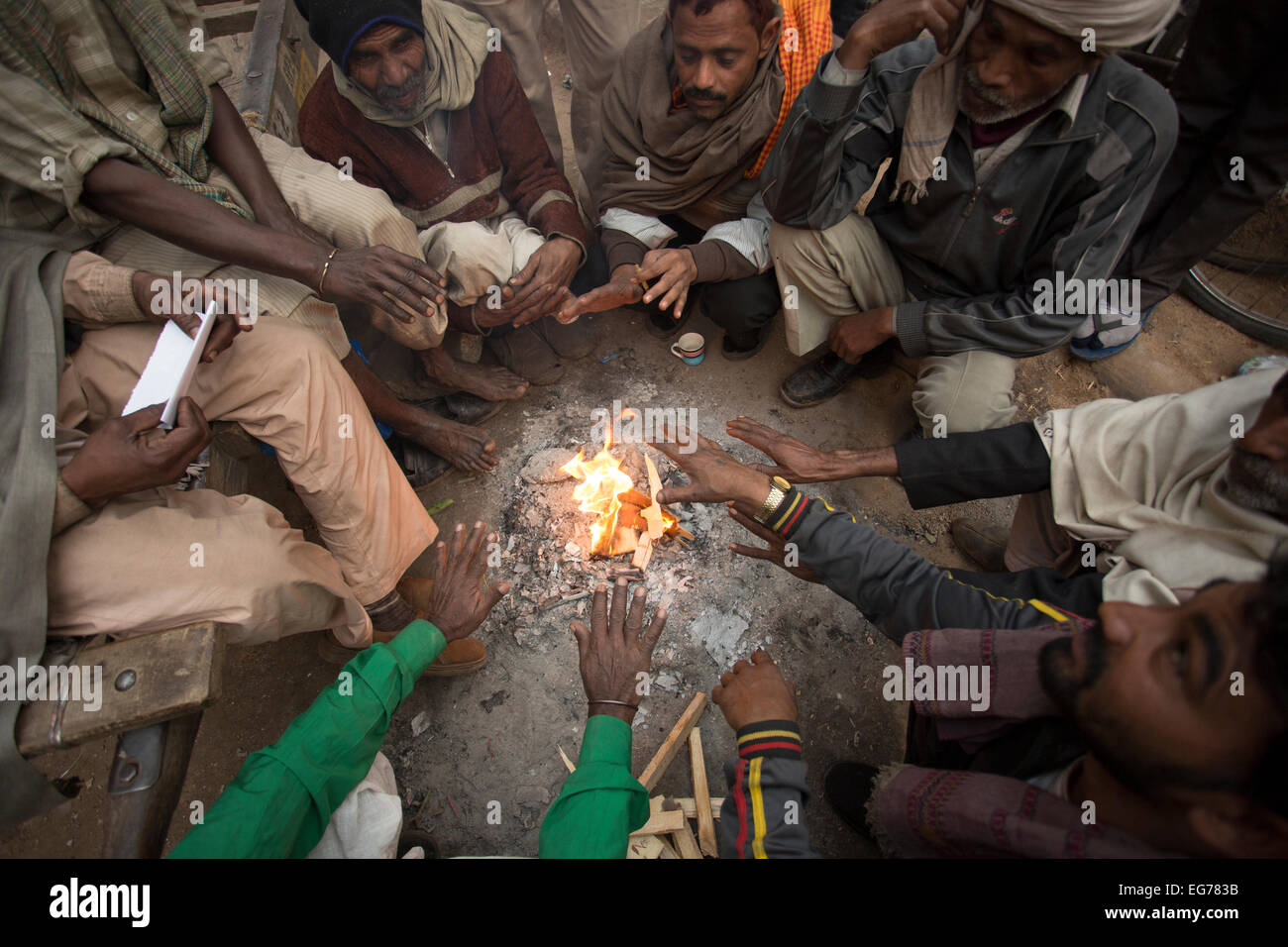 Men warm themselves by a fire in Old Delhi, India. Stock Photo