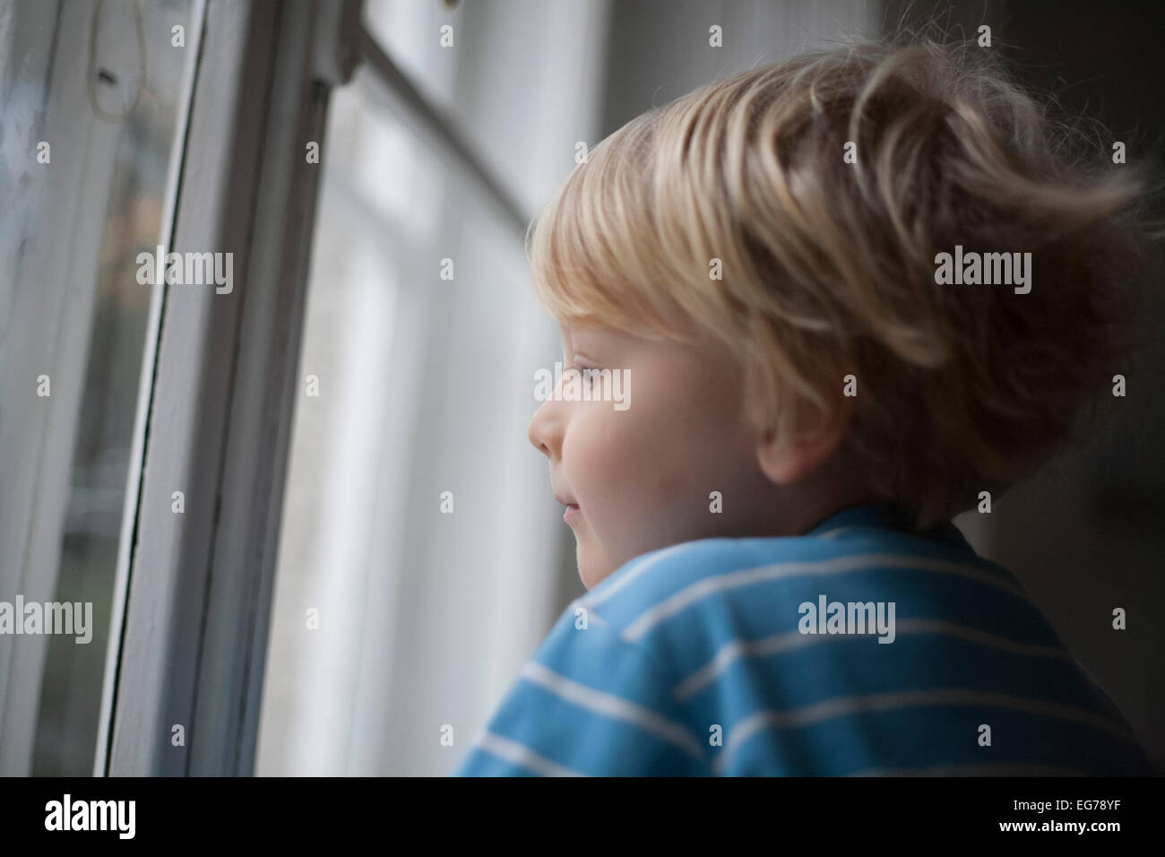 Profile of little boy looking out of window Stock Photo