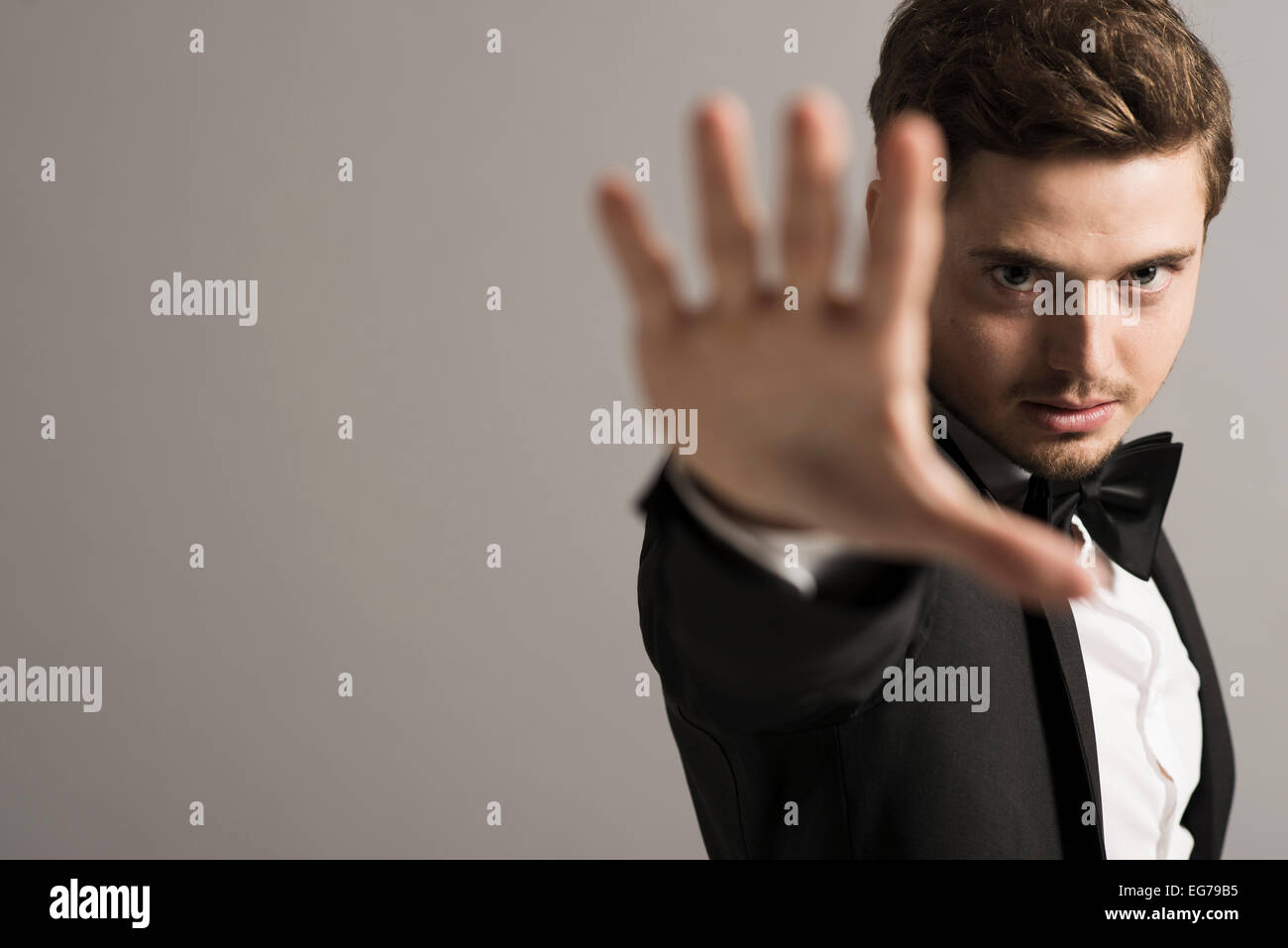 Man wearing tuxedo in front of grey background showing Stop gesture Stock Photo