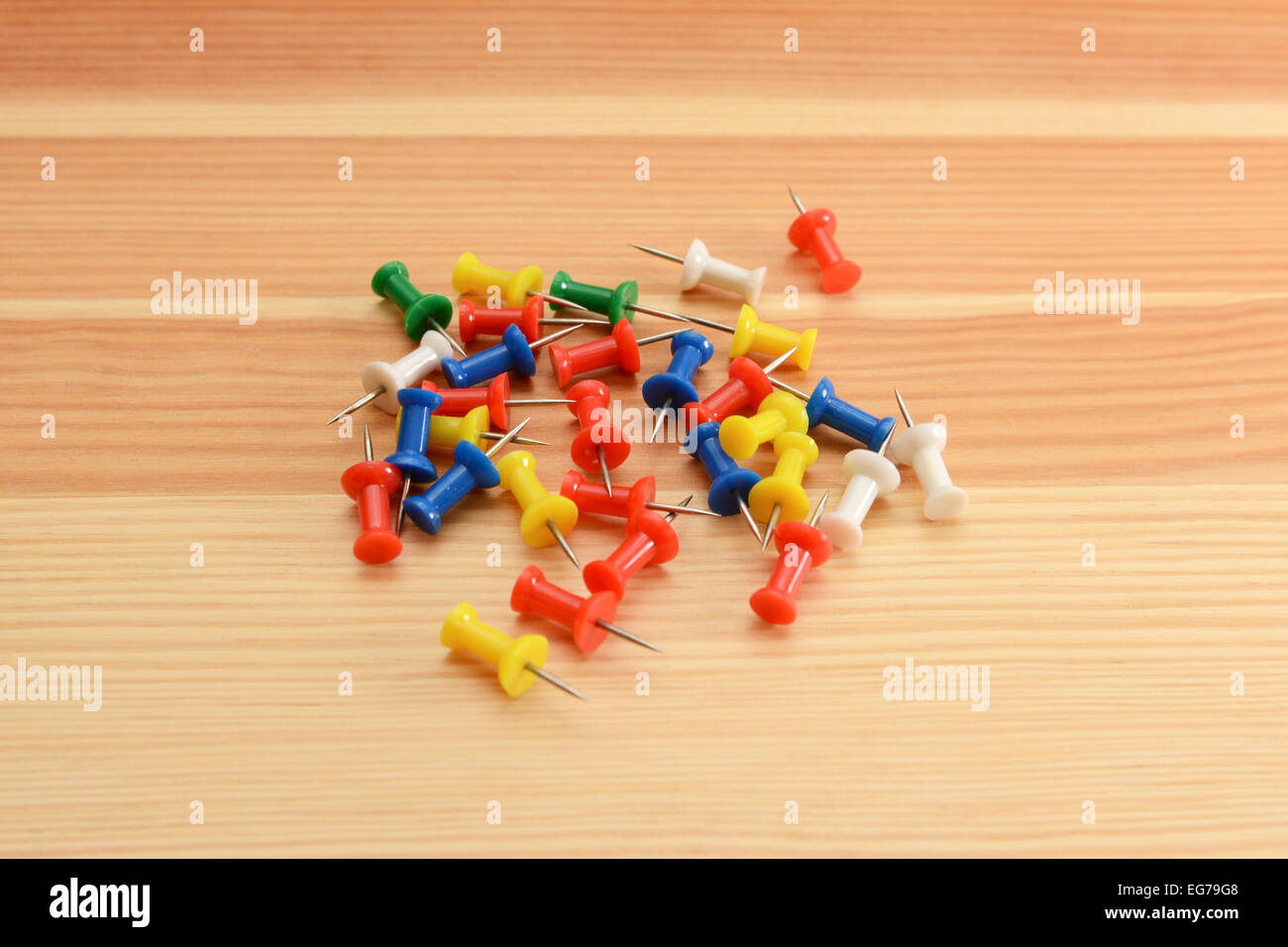 Coloured push pins - green, white, red, yellow and blue - on a wooden background Stock Photo