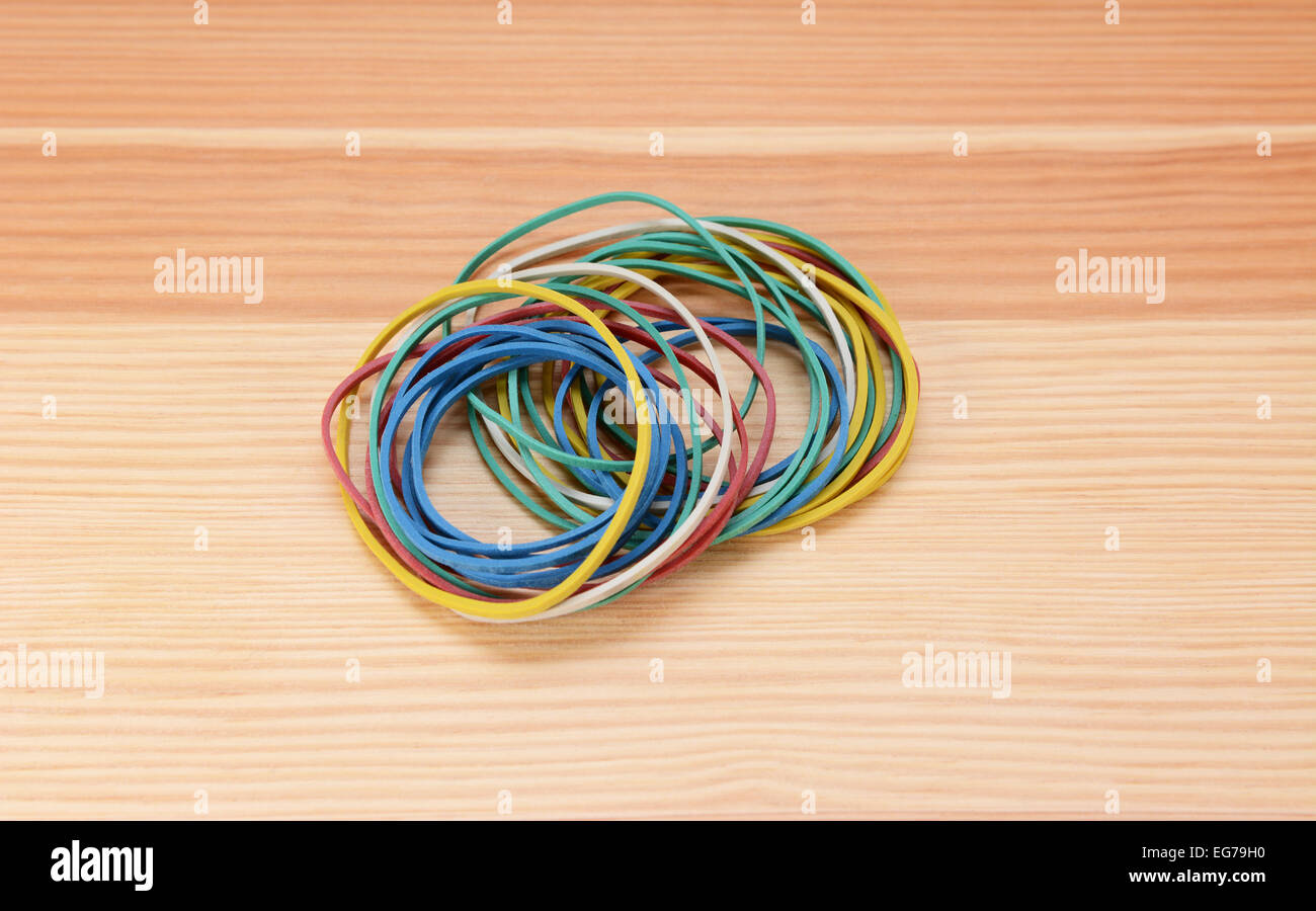Small neat pile of coloured rubber bands on a wooden background Stock Photo