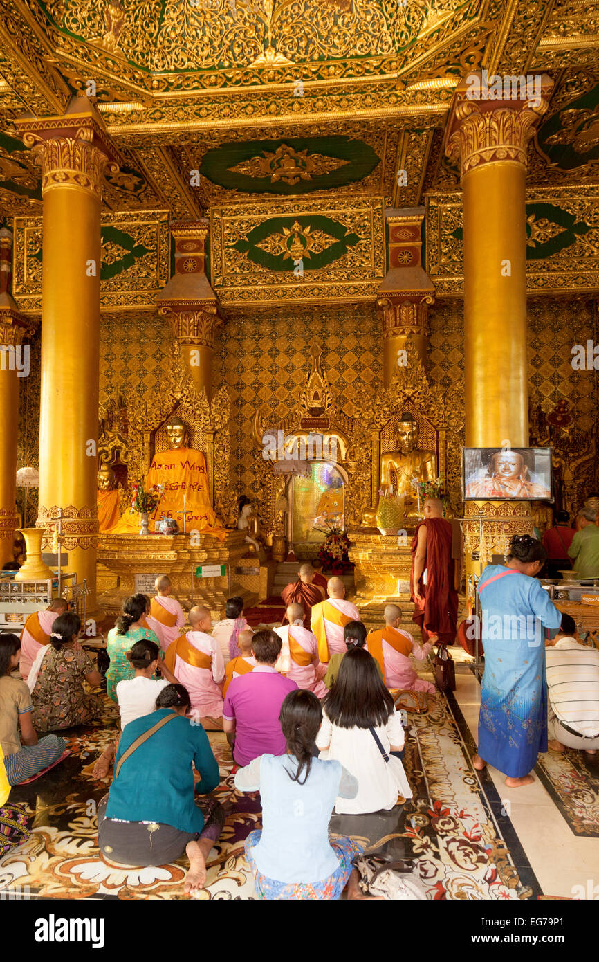 Buddhist people paying their respects to statues of Buddha, Shwedagon Pagoda, Yangon, Myanmar ( Burma ), Asia Stock Photo