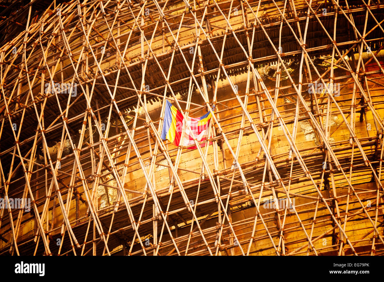 The buddhist flag flying in the bamboo scaffolding on the Shwedagon Pagoda during re-laying of the gold leaf, Yangon, Myanmar Stock Photo