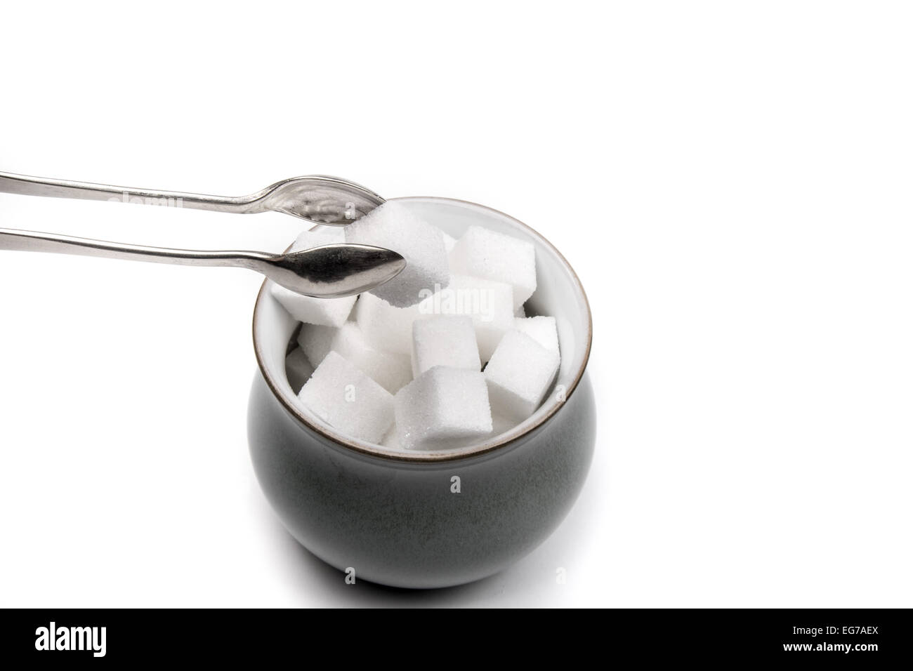 White Sugar Cubes in A Sugar Bowl With One Being Removed By A Pair of  Silver Tongs Stock Photo - Alamy