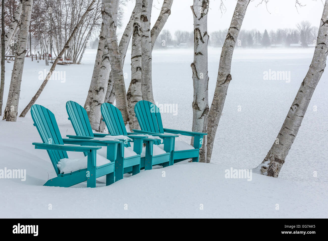 Adirondack chairs queued up as if waiting for summer along a lake shore