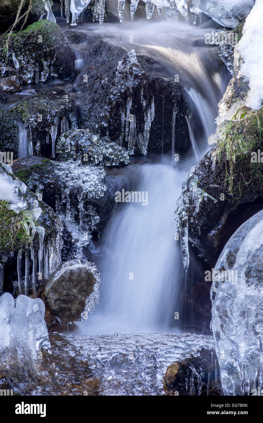Icicles on boulders and flowing water Stock Photo