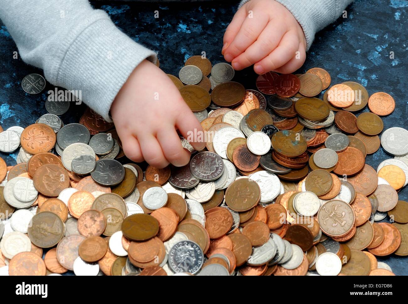 The hand of a 2 year old girl counting piggy bank money Stock Photo