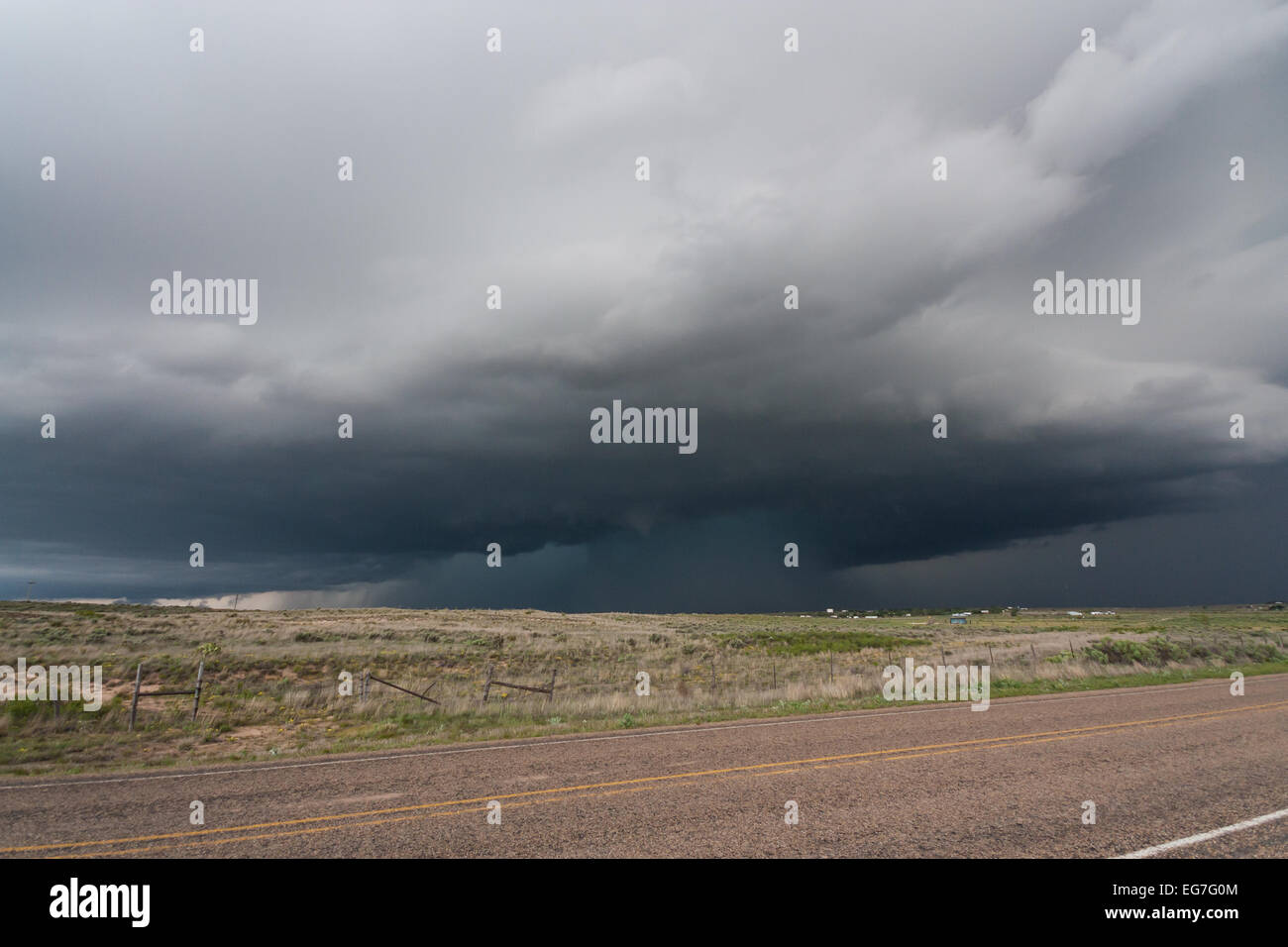 A powerful tornado warned supercell thunderstorm rolls across the Texas landscape with a large wall cloud and green hail core Stock Photo